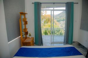 a bedroom with a bed and a large window at Celenika Resort in Kandy