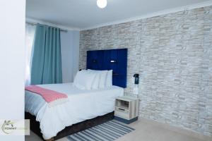 a bedroom with a bed and a brick wall at Towny Lodge in Kokstad