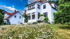 a white house with a field of flowers at Ferienwohnungen Meerblick Herde in Göhren