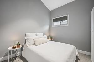 a white bedroom with a white bed and a window at The Ausly Architectural Coastal Retreat with pool pet friendly in Aldinga Beach