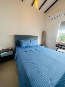 a bedroom with a bed with blue sheets and a window at The Galene Villa By Celestial Ceylon in Negombo