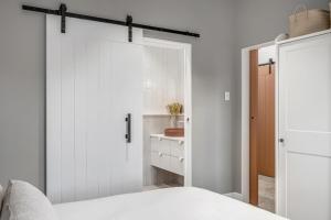 a white bedroom with a sliding barn door at The Ausly Architectural Coastal Retreat with pool pet friendly in Aldinga Beach