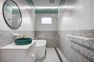 a white bathroom with a sink and a mirror at The Ausly Architectural Coastal Retreat with pool pet friendly in Aldinga Beach