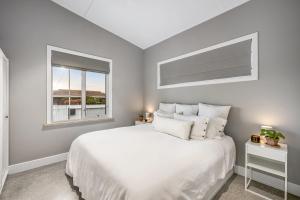 a white bedroom with a bed and a window at The Ausly Architectural Coastal Retreat with pool pet friendly in Aldinga Beach +14 photos