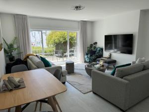 a living room with couches and a table and a tv at Bayview Apartment in Timaru