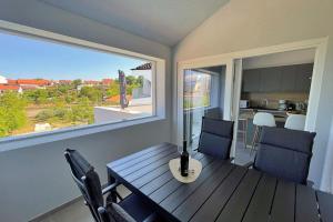 a dining room with a table and chairs and a large window at Apartments Bonum in Šilo