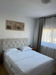 a bedroom with a large white bed with a window at Cazare Luxandra in Borşa