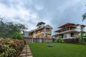 a large house with a yard with a frisbee at Gauri Villa by ELIVAAS With Pool, Lounge, Garden & Bathtub With 360 Panoramic Hill Views Near Waterfalls in Kasāra