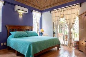 a bedroom with a bed with blue walls and a window at Casa Bella Brisa in Puerto Escondido