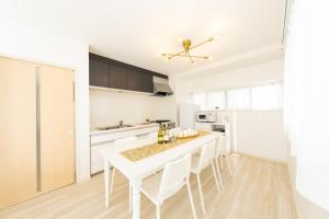 a white kitchen with a white table and chairs at Miraie Yokkaichi Hazunaka in Yokkaichi