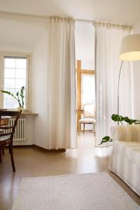 a living room with white curtains and a table and chair at Schloss Blumenfeld in Tengen