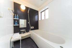 a bathroom with a white tub and a shower at Miraie Yokkaichi Hazunaka in Yokkaichi