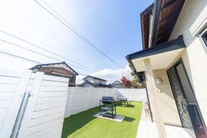 a small backyard with a white fence and a chair at Miraie Yokkaichi Hazunaka in Yokkaichi