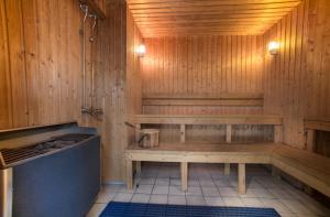 a wooden sauna with a bench and a shower at Home Hotel Park in Halden