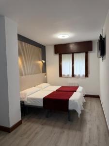 a bedroom with two beds with a red blanket at Pension Norte in Portugalete