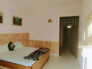 a bed in a room with a white wall at Suket homestay in Jhungi