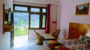 a bedroom with a bed and a table and a window at Suket homestay in Jhungi