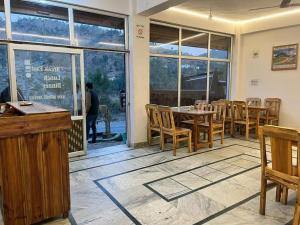 a dining room with tables and chairs and windows at Suket homestay in Jhungi