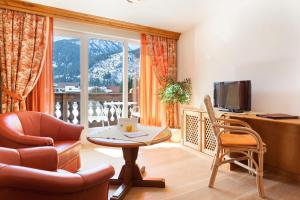 a living room with a chair and a table and a television at Das Traditionshotel Schwarzer Adler in Tannheim