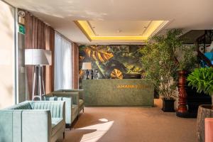a lobby with couches and a wall with a painting at Amana Hotel Airport in Ho Chi Minh City