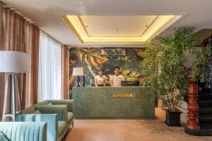 two people standing at a counter in a hotel lobby at Amana Hotel Airport in Ho Chi Minh City