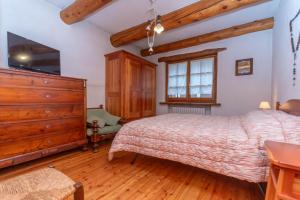 a bedroom with a large bed and a wooden dresser at Tabia Maredane in Falcade