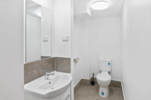 a white bathroom with a toilet and a sink at Annerley Motor Inn in Brisbane