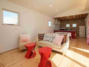 a living room with a couch and two red stools at VILLA YAHACHI GARDEN in Tahara