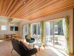a living room with a wooden ceiling and glass windows at VILLA YAHACHI GARDEN in Tahara