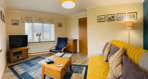 a living room with a yellow couch and a tv at Maesyfelin Isaf Apartment in Llanybyther