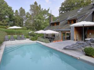 スパにあるAttractive Holiday Home in Spa with Swimming Poolの家の隣のスイミングプール(椅子、パラソル付)
