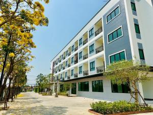 a large white building with windows on a street at SK Residence & resort in Ban Nong Pla Mo