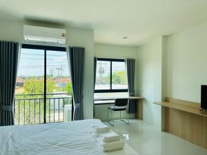 a bedroom with a bed and a desk and a balcony at SK Residence & resort in Ban Nong Pla Mo