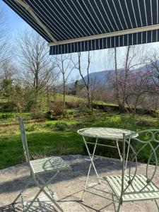 a table and two chairs under an umbrella at Gîte Asaliah in Sainte-Colome