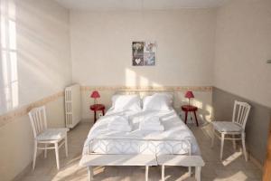 a bedroom with a white bed and two chairs at LES CHESNEAUX in Loches