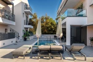 a patio with chairs and umbrellas next to a swimming pool at Aqua Lora in Nikiana