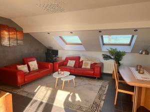 a living room with two red couches and a table at Modern Apartment in Annemasse 15 mins to Geneva with private free parking in Vétraz-Monthoux