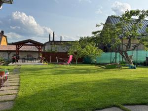 a green yard with chairs and a tree at Čučo Privat in Tatranska Strba