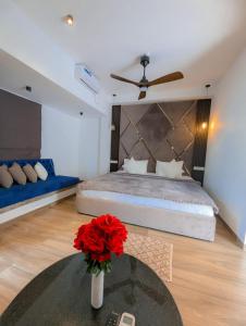 a bedroom with a bed and a table with a vase with red flowers at White Tree Apartment in Bentota