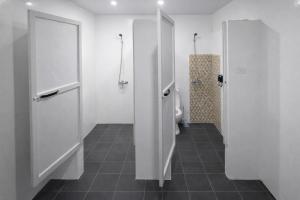 a white bathroom with a toilet and a shower at Islanders Hostel Siquijor in San Juan +40 photos