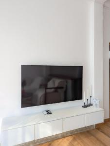 a living room with a large tv on a white wall at White Tree Apartment in Bentota