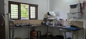 a kitchen with a counter and a sink andwindows at Brighton Hostel Stays in Sultan Bathery