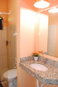 a bathroom with a sink and a toilet and a mirror at Hotel Rusticos in Conceição da Barra