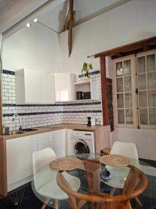 a kitchen with a glass table and white cabinets at Ô Privilège studio jacuzzi clim en centre-ville de Saint-Pierre in Saint-Pierre
