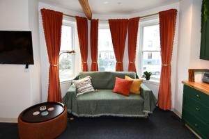 a living room with a green couch and orange curtains at HighRoad Washington DC in Washington, D.C.