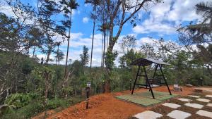 a swing set in the middle of a forest at Vidman Homey Huts in Tindummal
