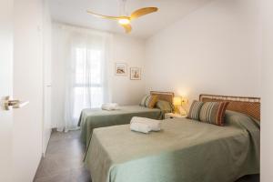 a room with two beds and a ceiling fan at AT Ponent I B3 in La Playa de la Torre de Piles +10 photos