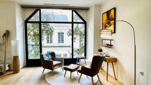 a living room with chairs and a large window at - Magnifique appartement climatisé 92m2, spacieux et cosy, au cœur de Vichy in Vichy