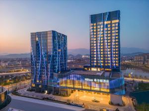 two tall buildings in a city at night at Hilton Quzhou in Quzhou