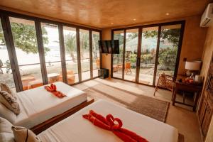 a room with two white beds with red bows at Sunset at Las Cabanas in El Nido